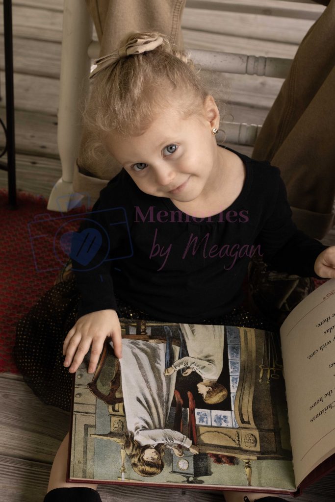 Little girl with a book on a porch. 